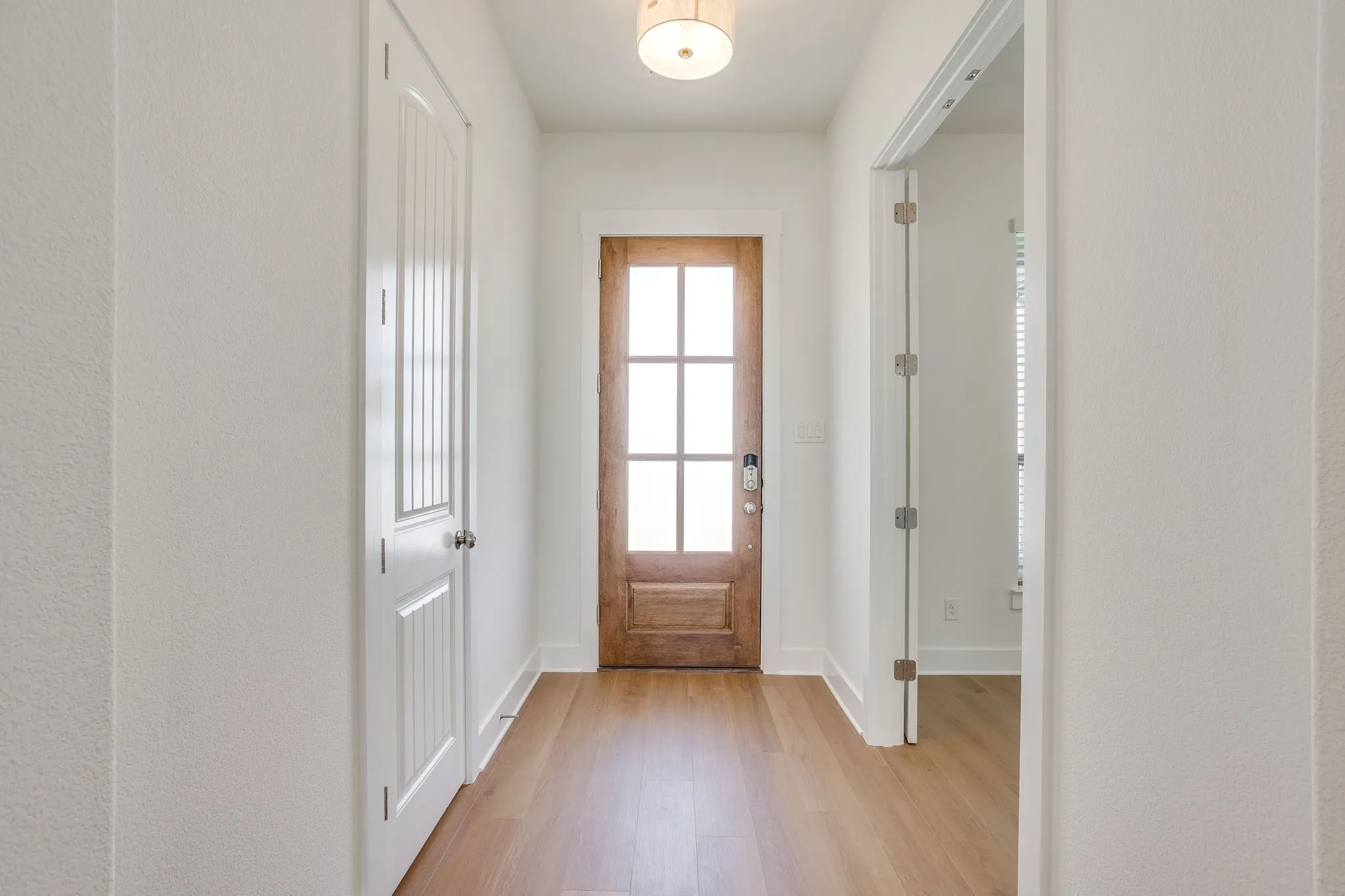 Entryway featuring wood-finish flooring, a wood-panelled door with frosted glass, and a flush-mount ceiling fixture