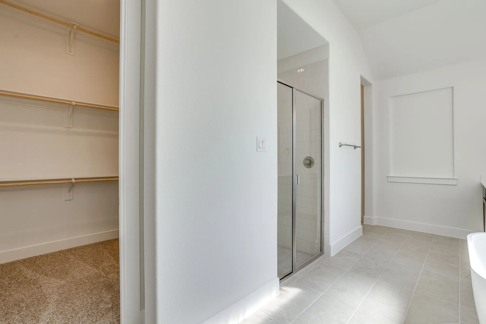 Spacious bathroom featuring a glass-enclosed shower, freestanding tub, and large format floor tiling