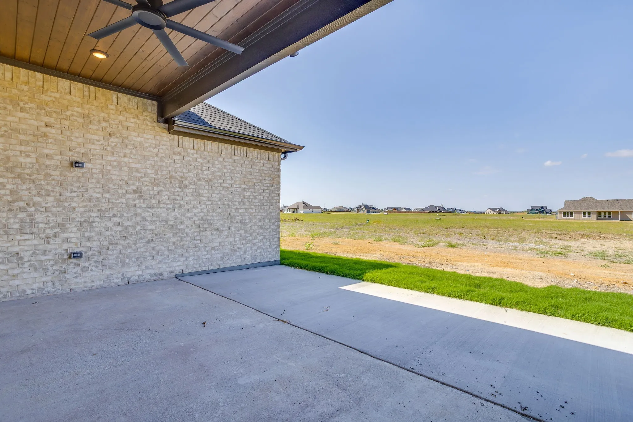 Covered outdoor patio with a ceiling fan, recessed lighting, and a light-colored brick exterior