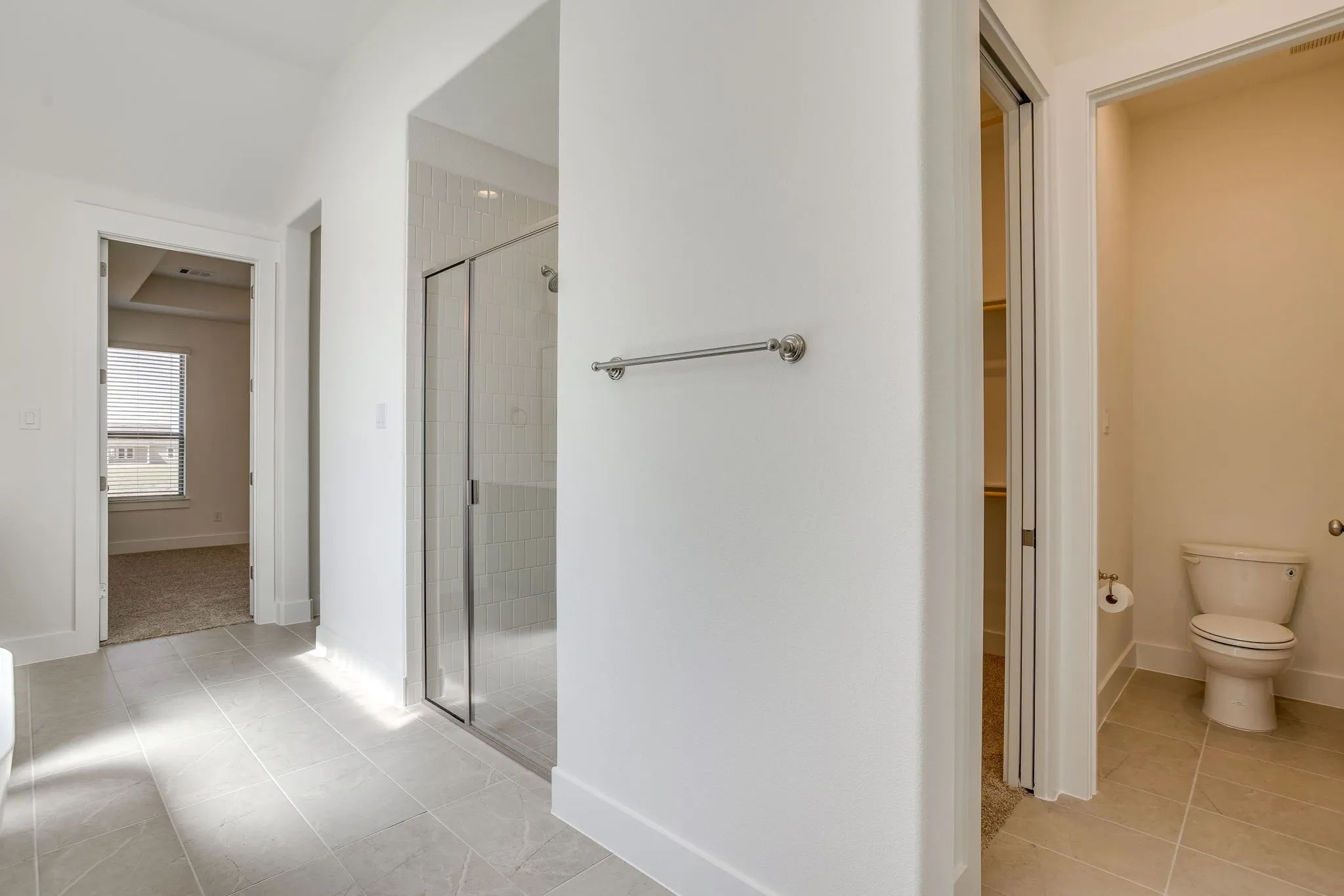Tiled flooring, glass-enclosed shower, built-in shelving, and a toilet