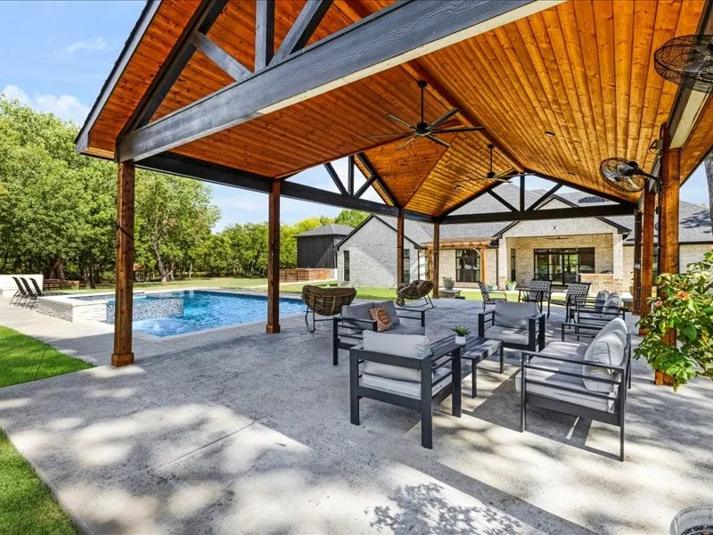 Covered patio with a wood-finish ceiling, exposed beams, and concrete flooring