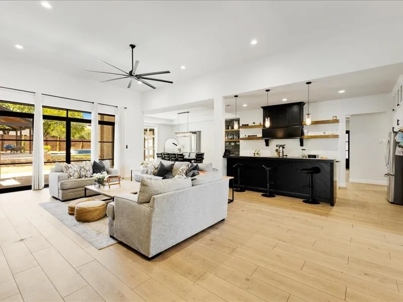 Spacious living area featuring wood-finish flooring, a large ceiling fan, recessed lighting, and expansive multi-pane windows