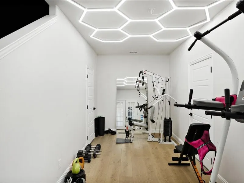 Recessed hexagonal ceiling lighting, wood-finish flooring, and white paneled doors