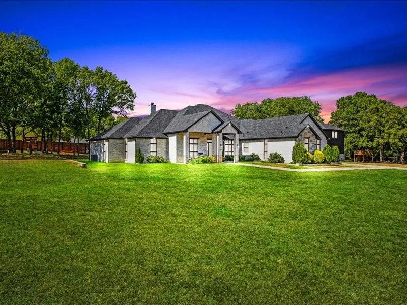 Expansive front lawn with mature trees and a fenced perimeter