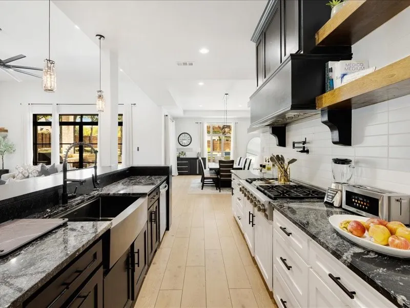 Kitchen featuring stone countertops, a large farmhouse sink, stainless steel appliances, and wood-finish flooring