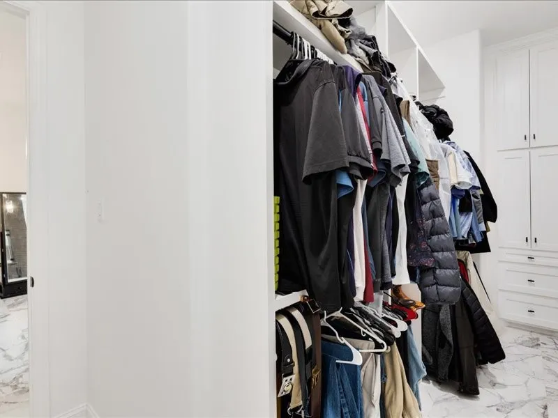 Built-in closet system featuring white shelving, hanging rods, and integrated cabinetry