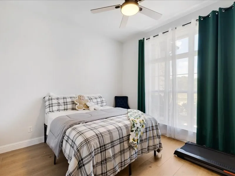 Recessed lighting, ceiling fan, wood-finish flooring, and large window with sheer and solid curtains