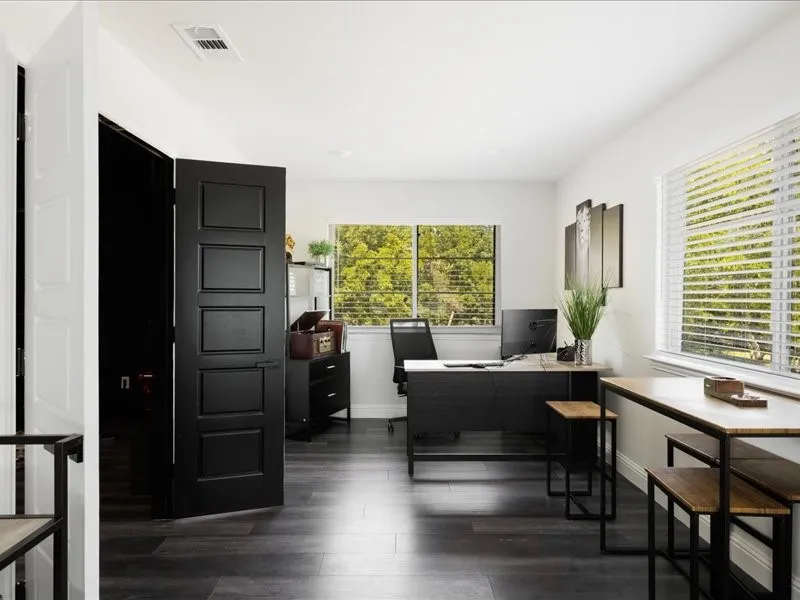 Room featuring wood-finish flooring, white walls, and multiple windows with horizontal blinds
