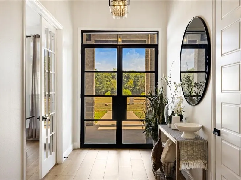 Entryway featuring a black-framed glass door, wood-finish flooring, and a crystal chandelier