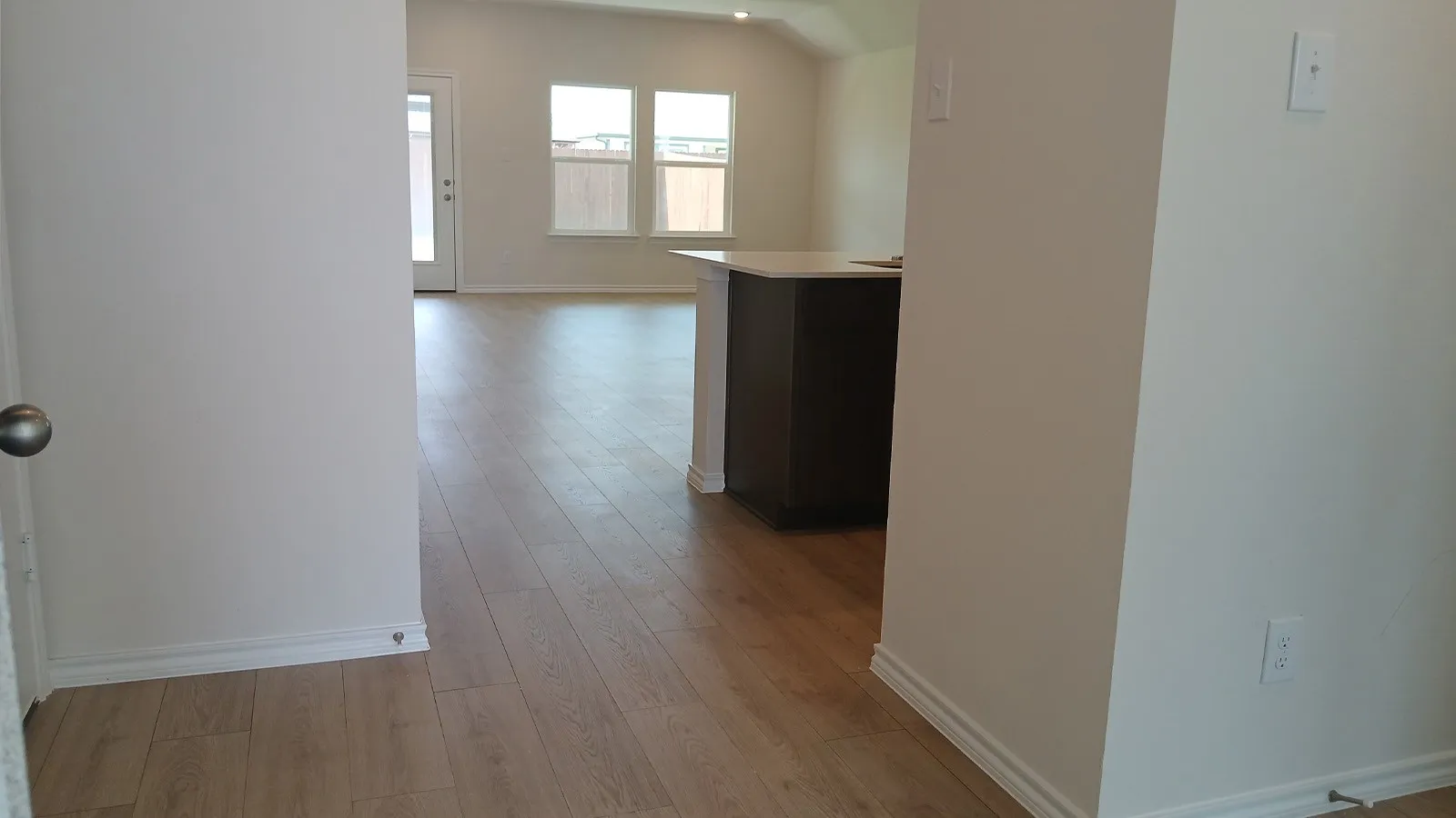 Open-concept interior featuring wood-finish flooring, white walls, and bright natural light