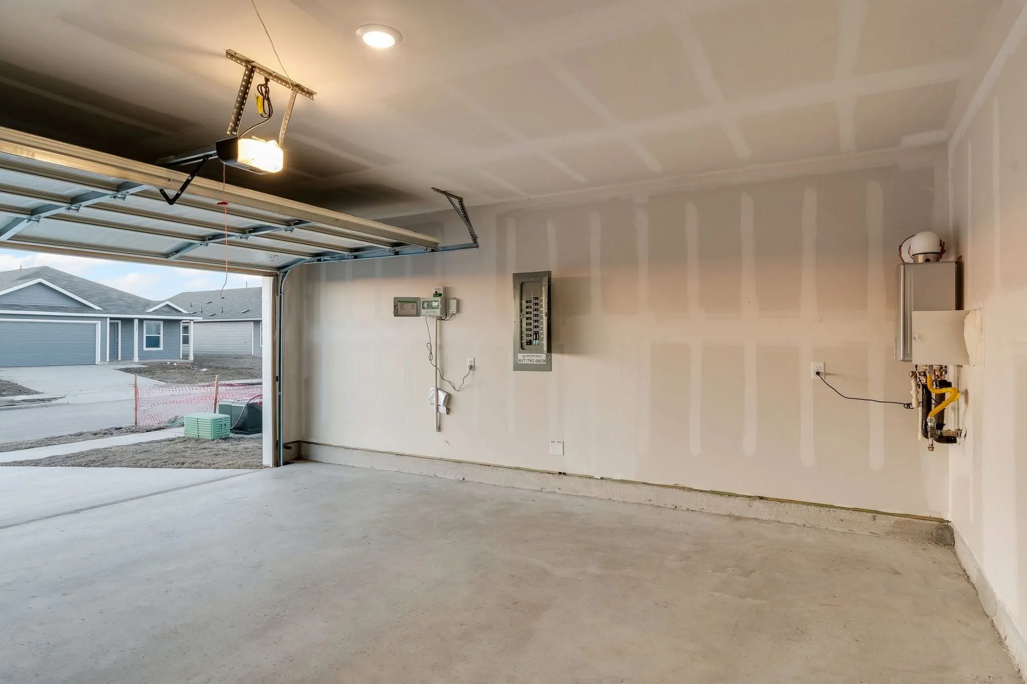 Garage with water heater, electric panel, and a garage door opener