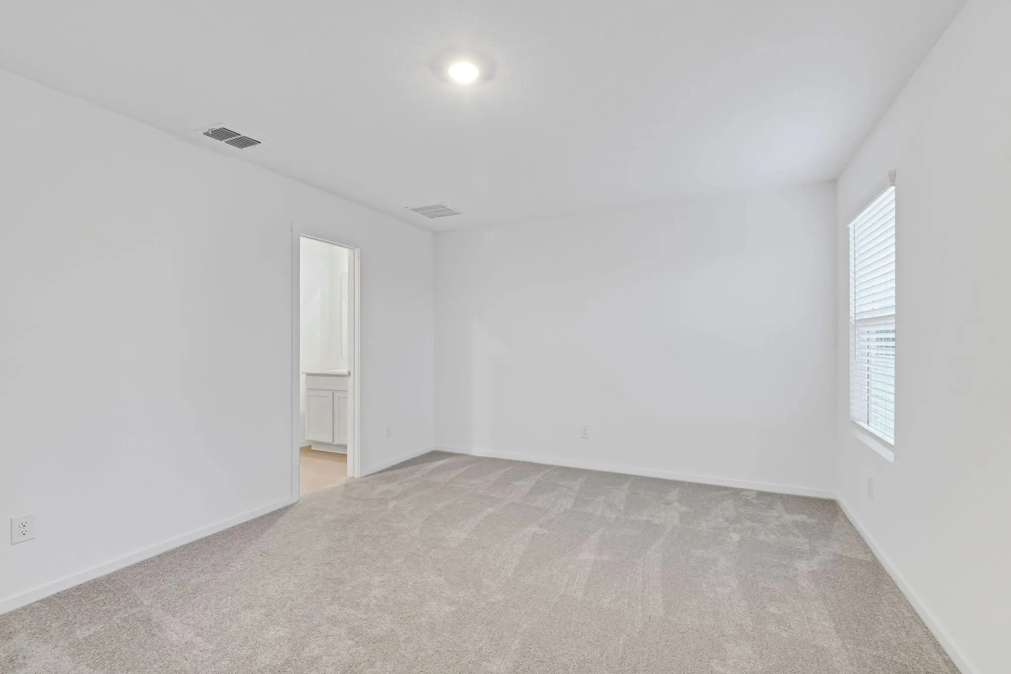 Unfurnished room with baseboards, visible vents, and light colored carpet