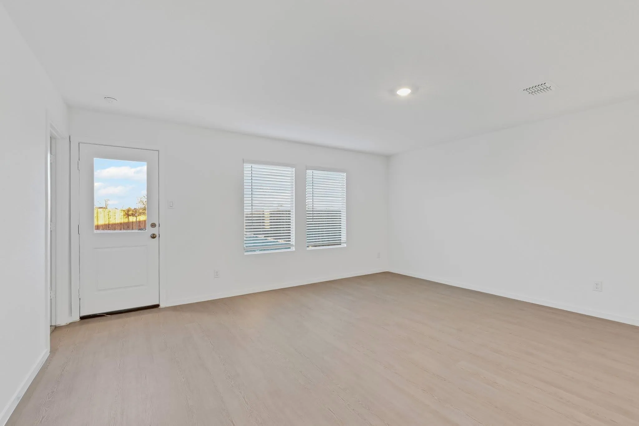 Unfurnished room featuring plenty of natural light, visible vents, baseboards, and light wood-style flooring