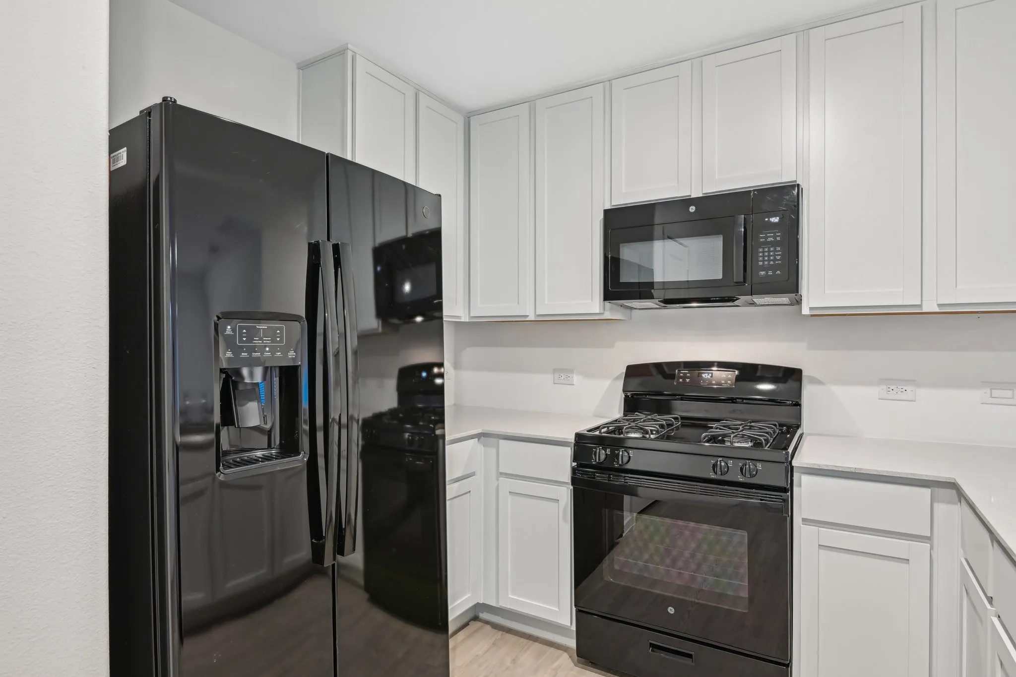 Kitchen featuring white cabinets, light hardwood / wood-style flooring, and black appliances