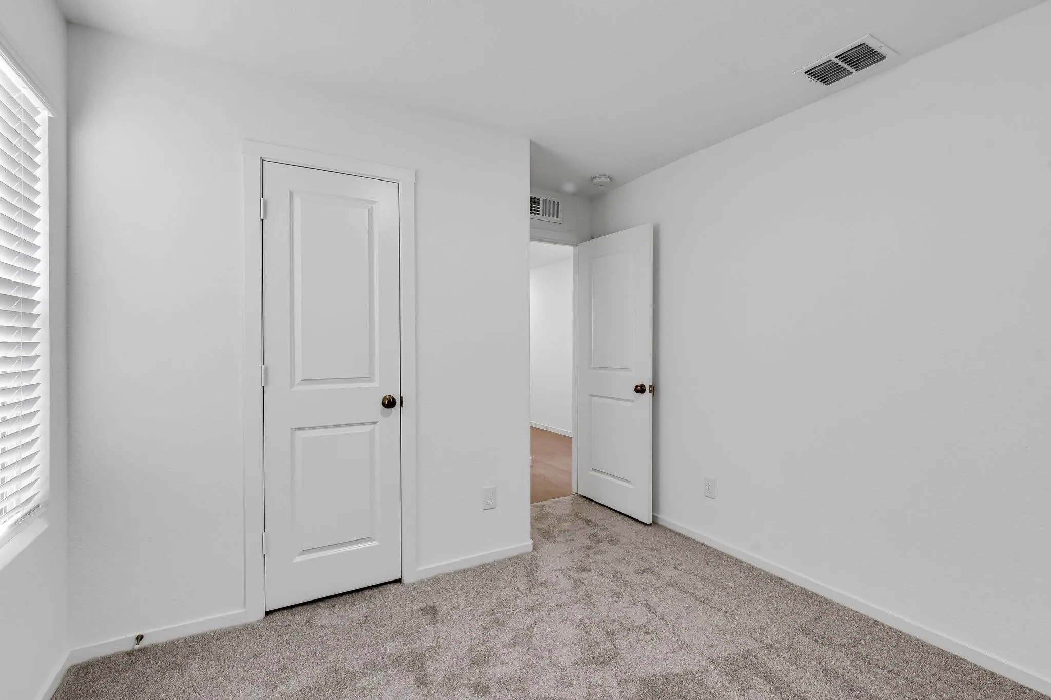 Unfurnished bedroom featuring visible vents, light carpet, and baseboards