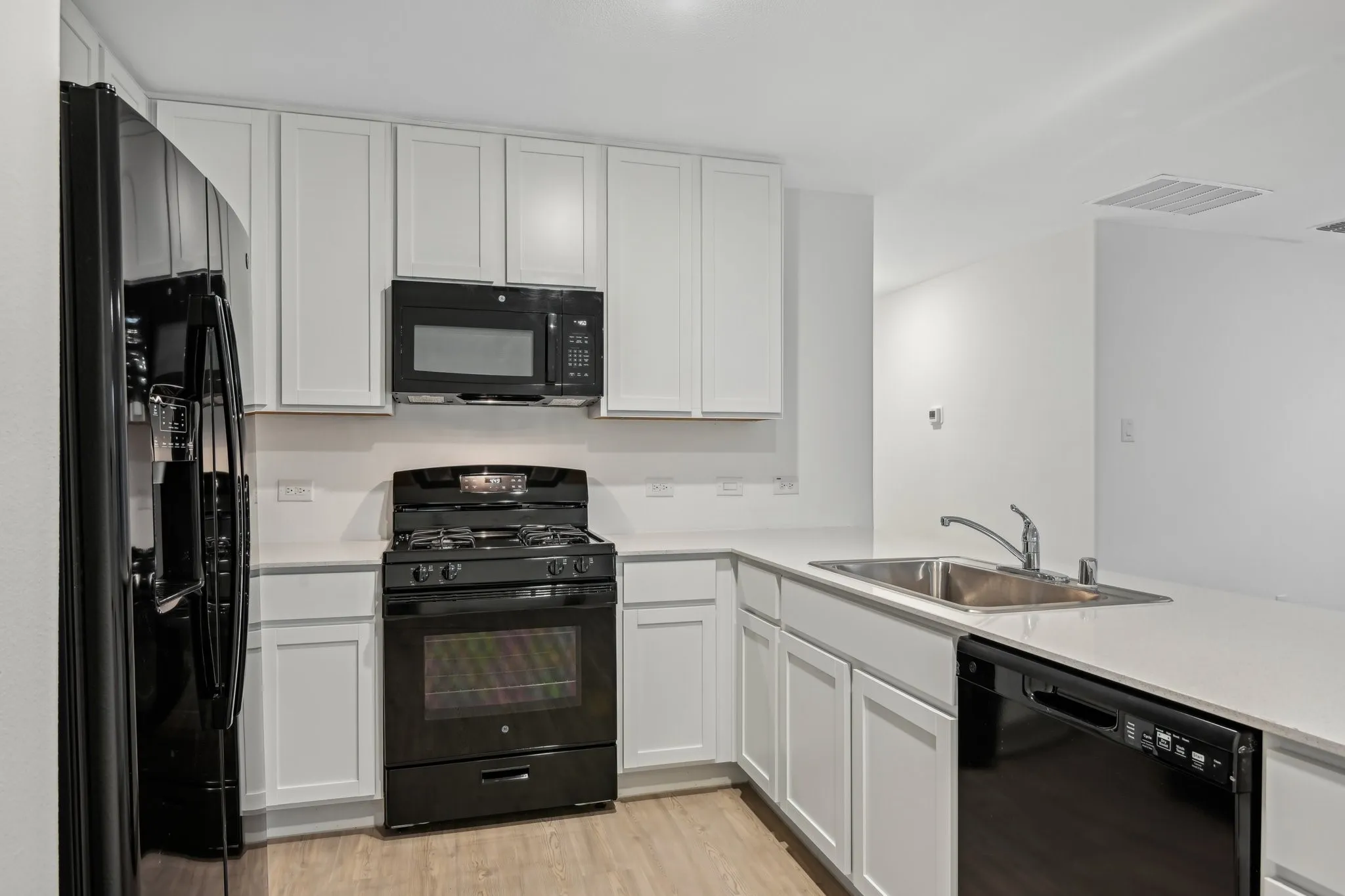 Kitchen with white cabinetry and black appliances