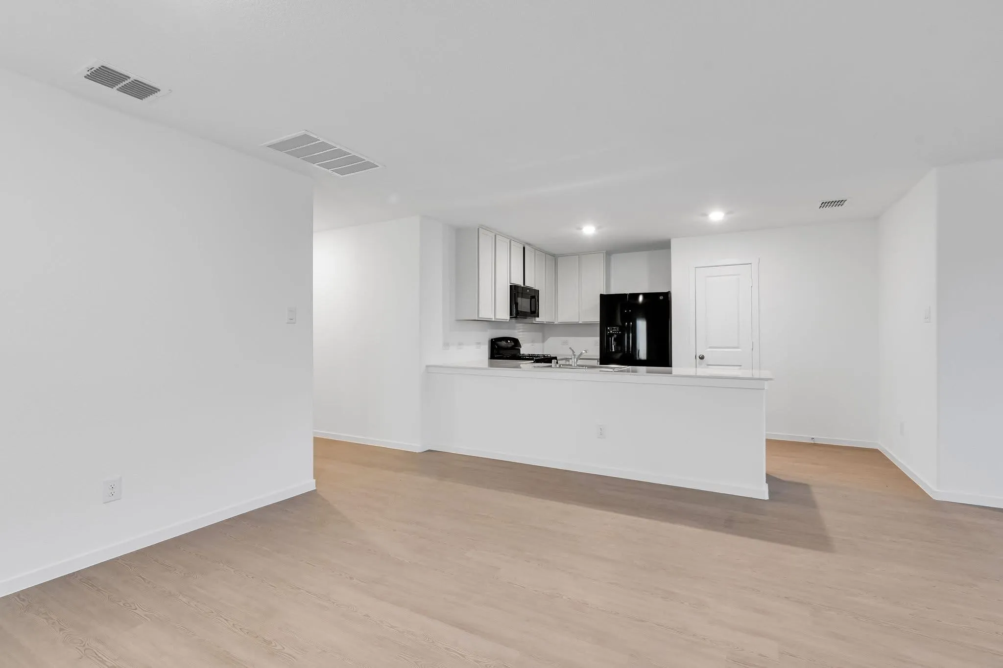 Kitchen featuring light countertops, white cabinets, visible vents, and black appliances