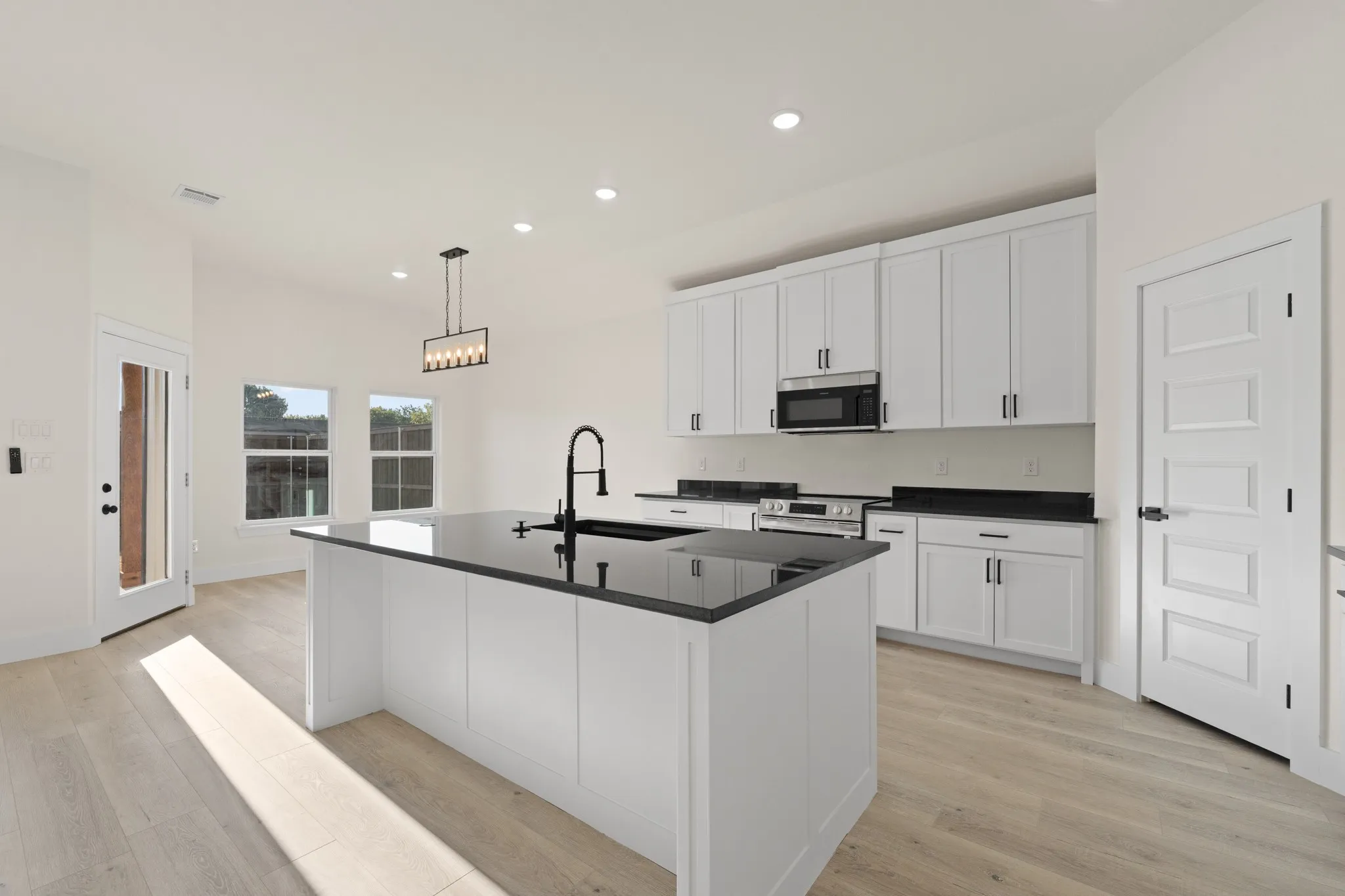 Kitchen featuring a central island, white cabinetry, dark countertops, built-in microwave, and wood-finish flooring