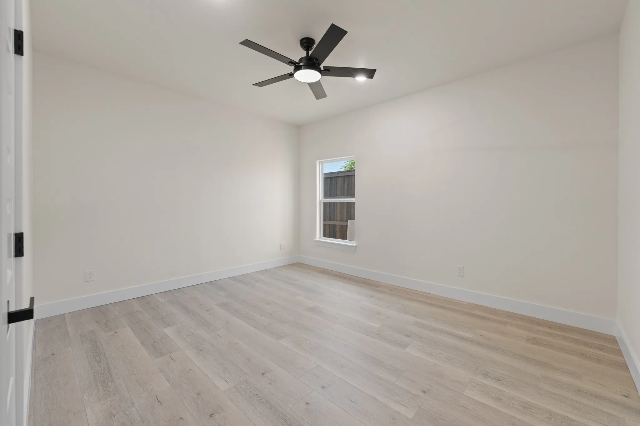 Bedroom 1 Light wood-finish flooring, white walls, and a modern ceiling fan with integrated lighting.