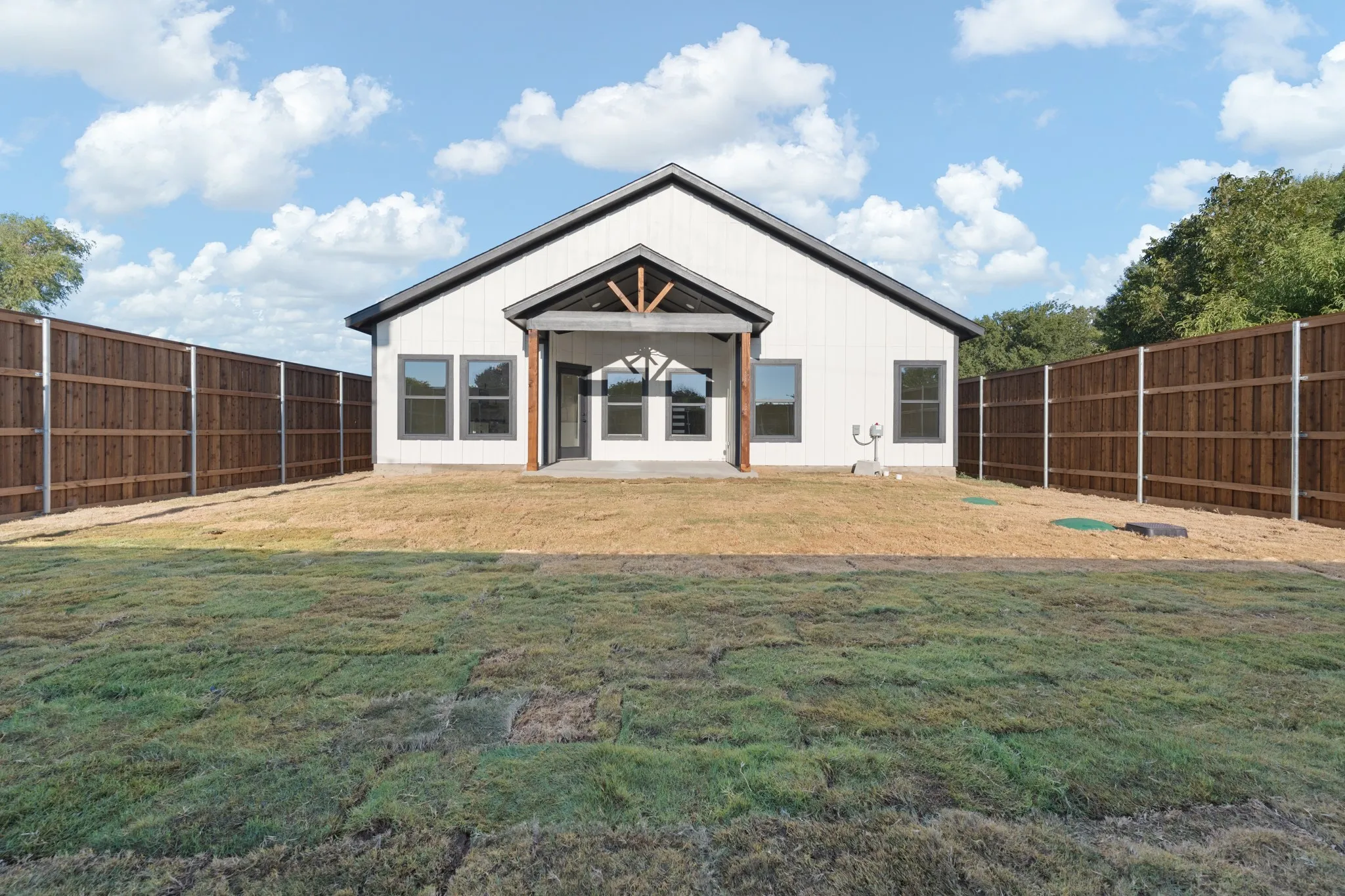 Private backyard with a newly installed wooden privacy fence, a covered patio, and a gabled roofline