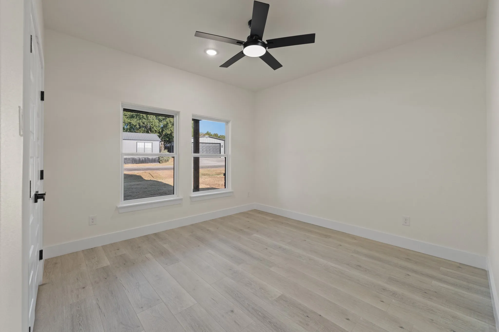 Bedroom 2 Light wood-finish flooring, white walls, and a modern ceiling fan with integrated lighting.