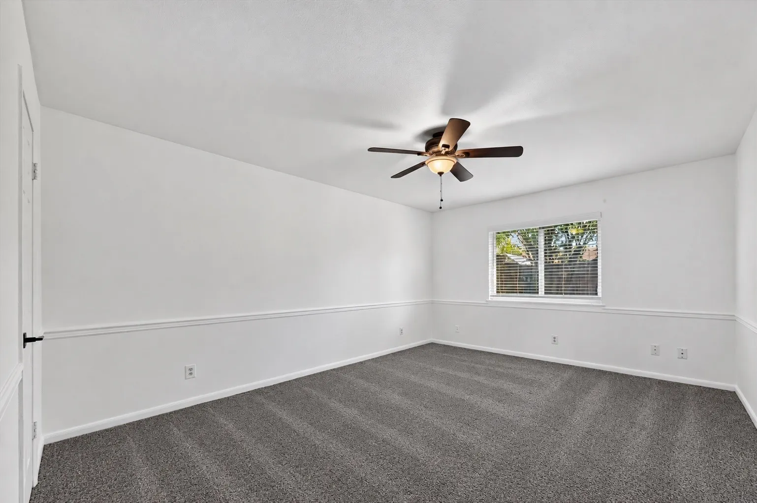 Neutral wall finishes with wainscoting detail, ceiling fan with integrated lighting, and a window with horizontal blinds