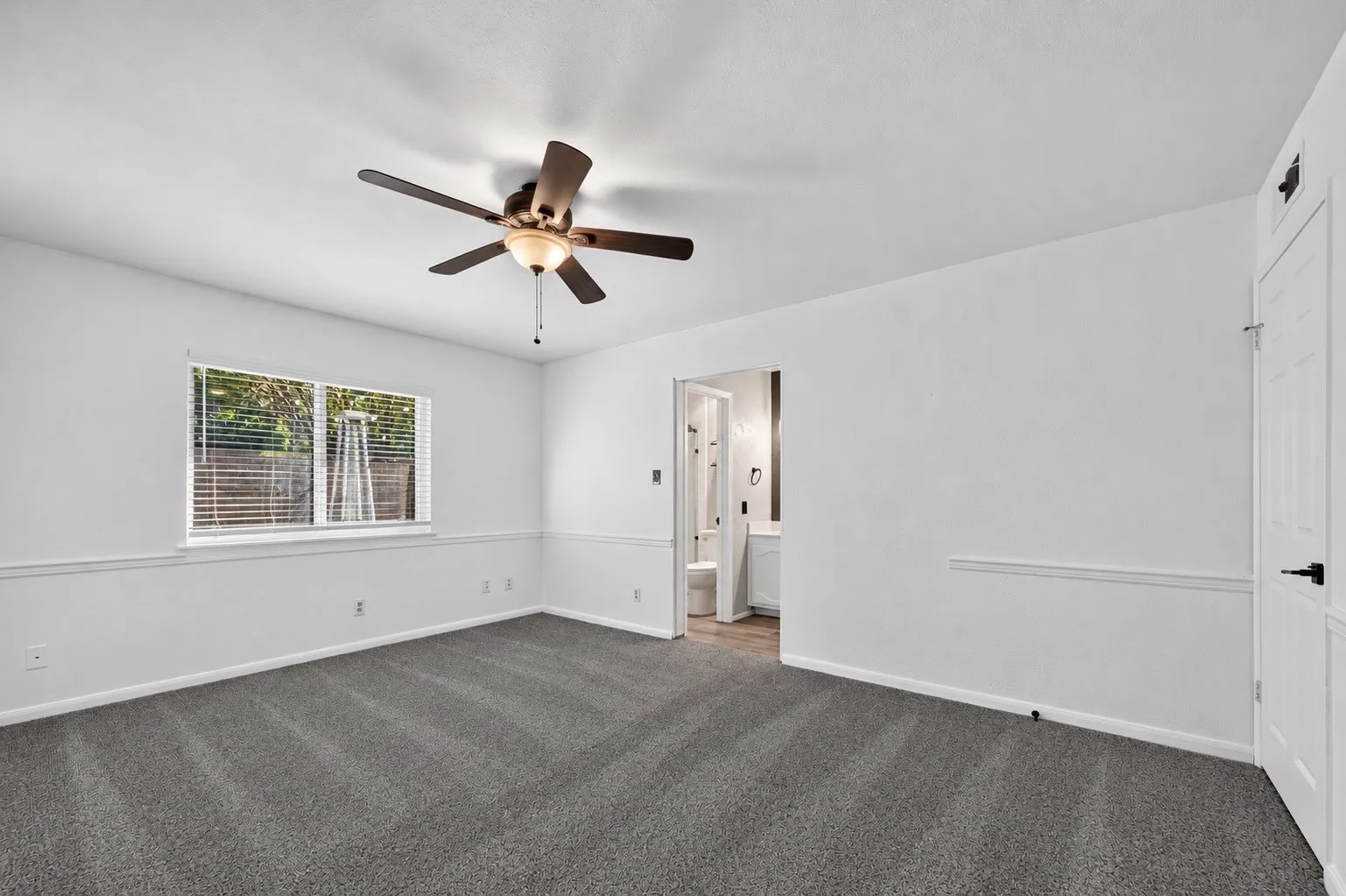 Wall-to-wall carpeting with a ceiling fan light fixture