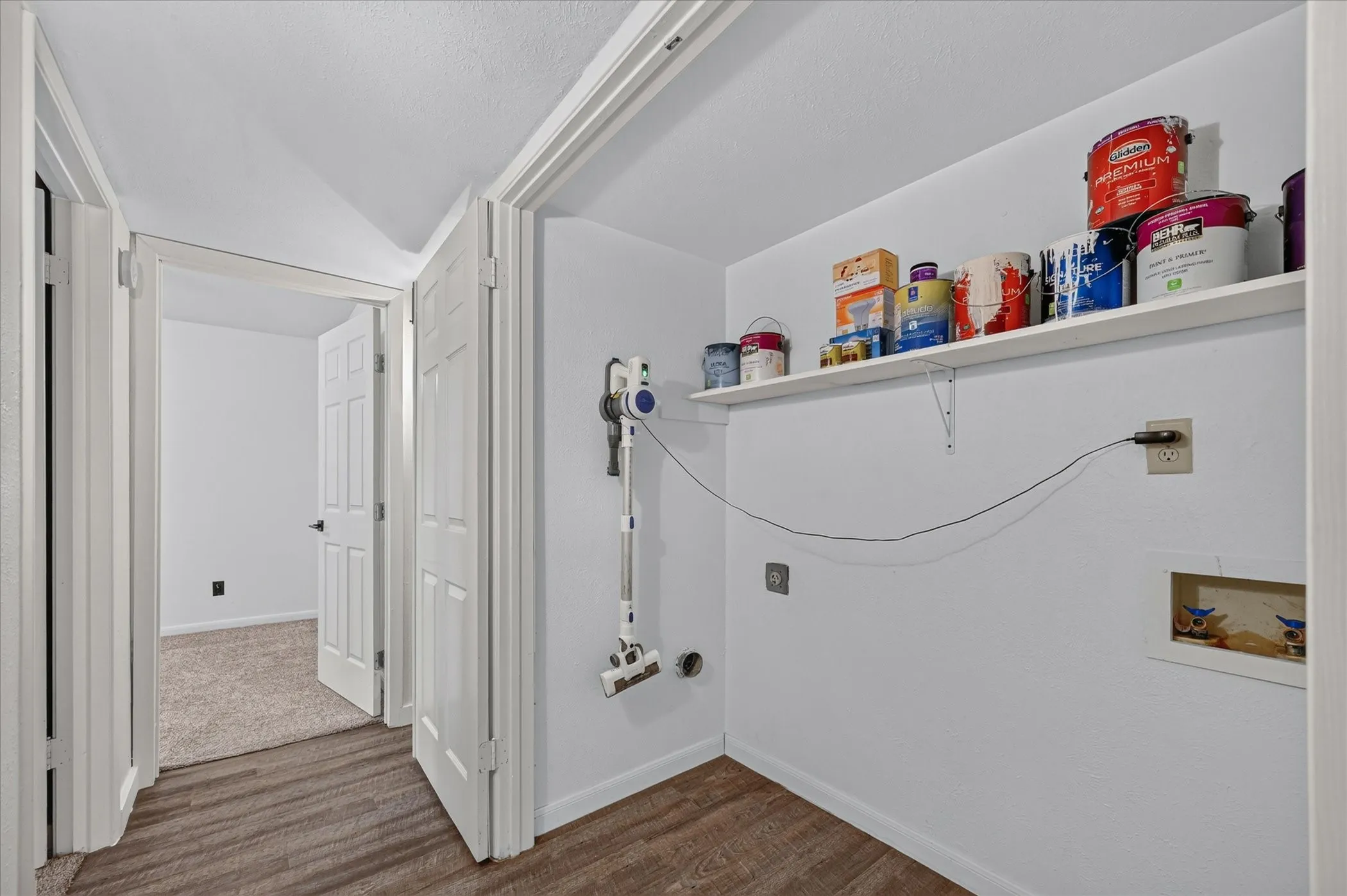 Laundry area with wood-finish flooring, a wall-mounted shelf, and appliance hookups