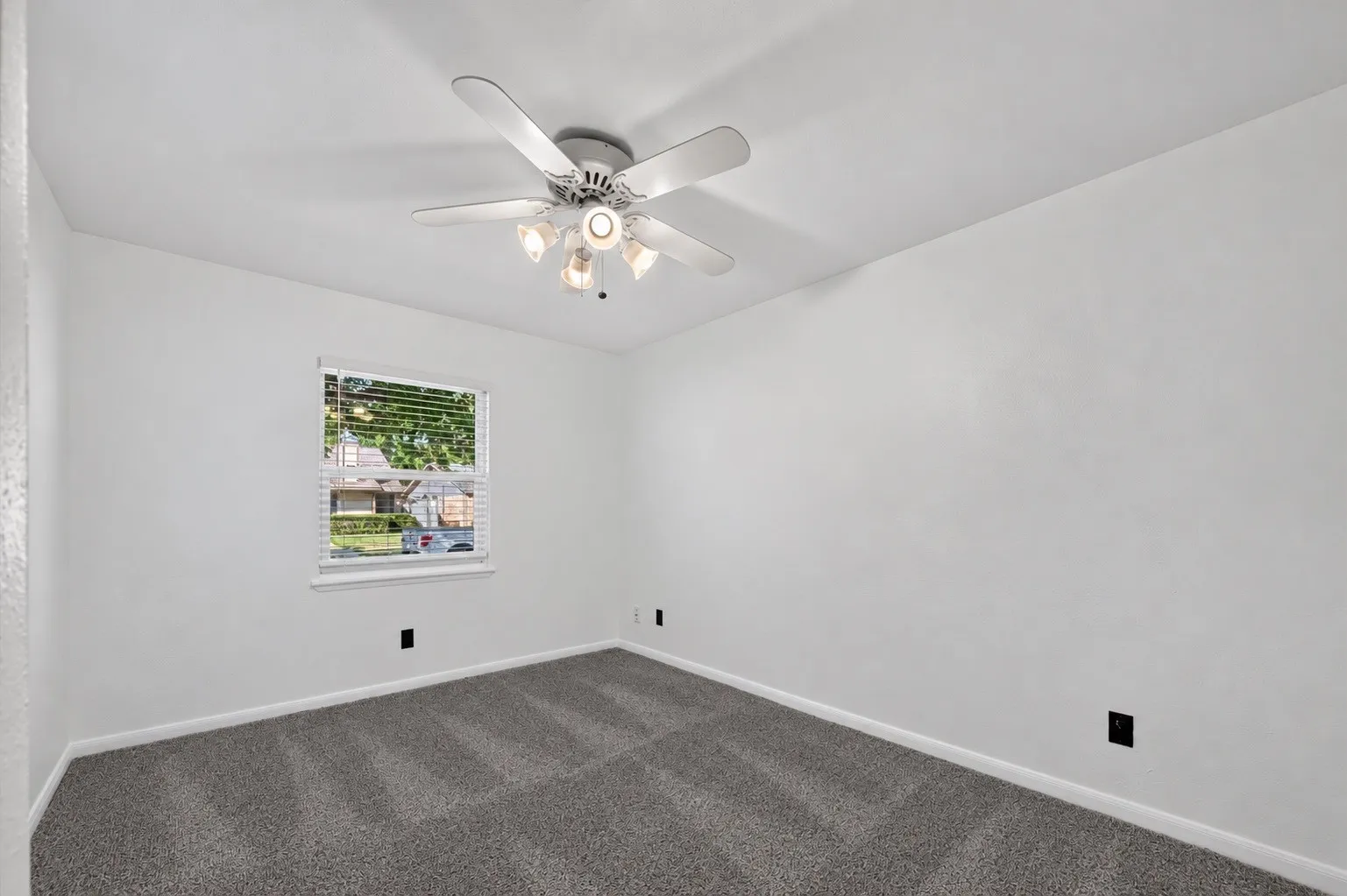 Neutral wall colors, textured carpeting, and a ceiling fan with integrated lighting