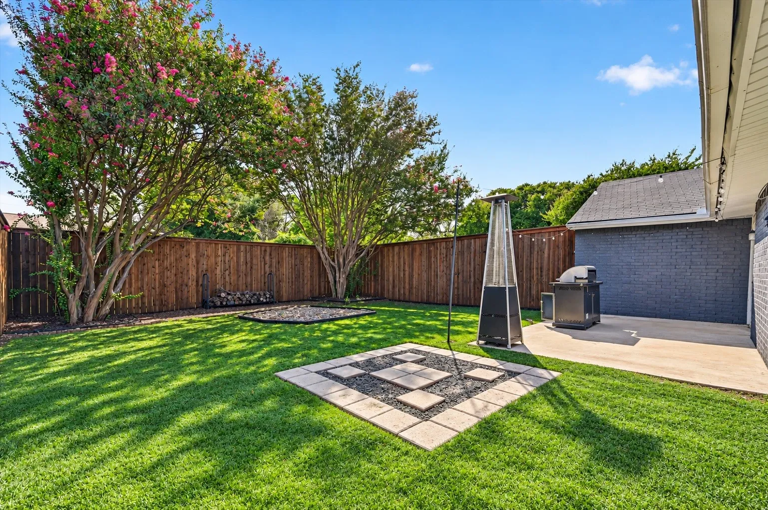 Expansive backyard with a manicured lawn, full wood privacy fence, and mature trees