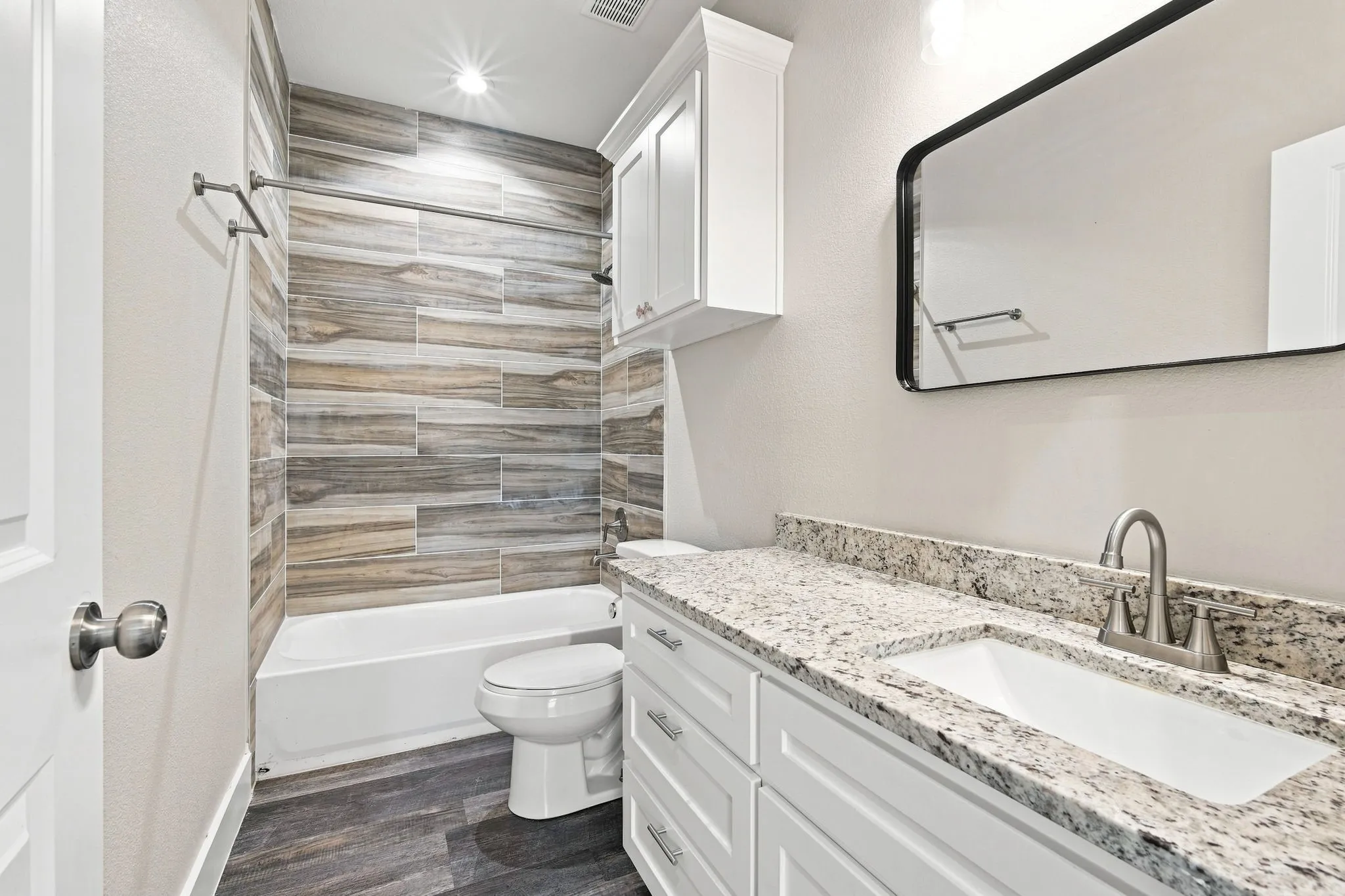 White vanity with a light-colored granite-style countertop, undermount sink, and brushed nickel faucet