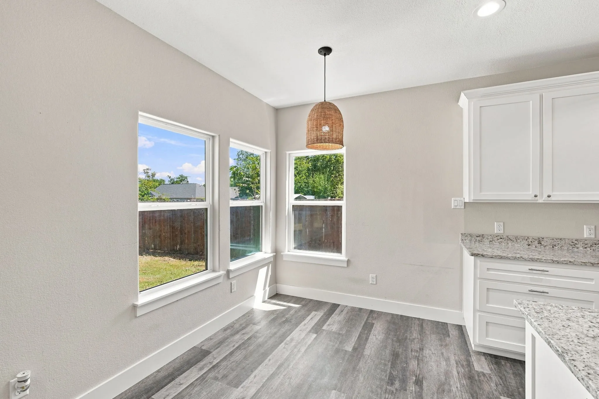 White shaker cabinetry with granite countertops, wood-finish flooring, recessed lighting, and a pendant light fixture
