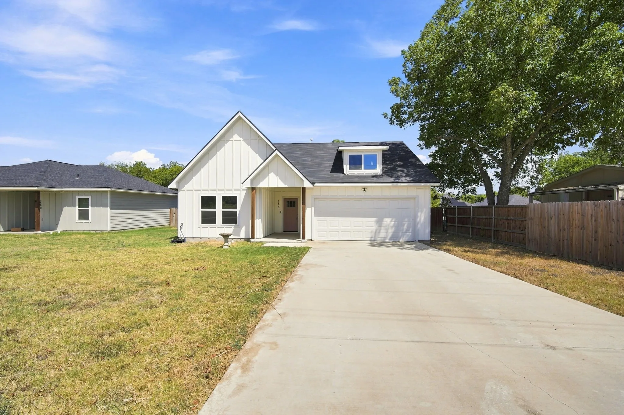 Modern farmhouse-style exterior with vertical siding, gabled roofline, front porch, and an attached garage with a concrete driveway