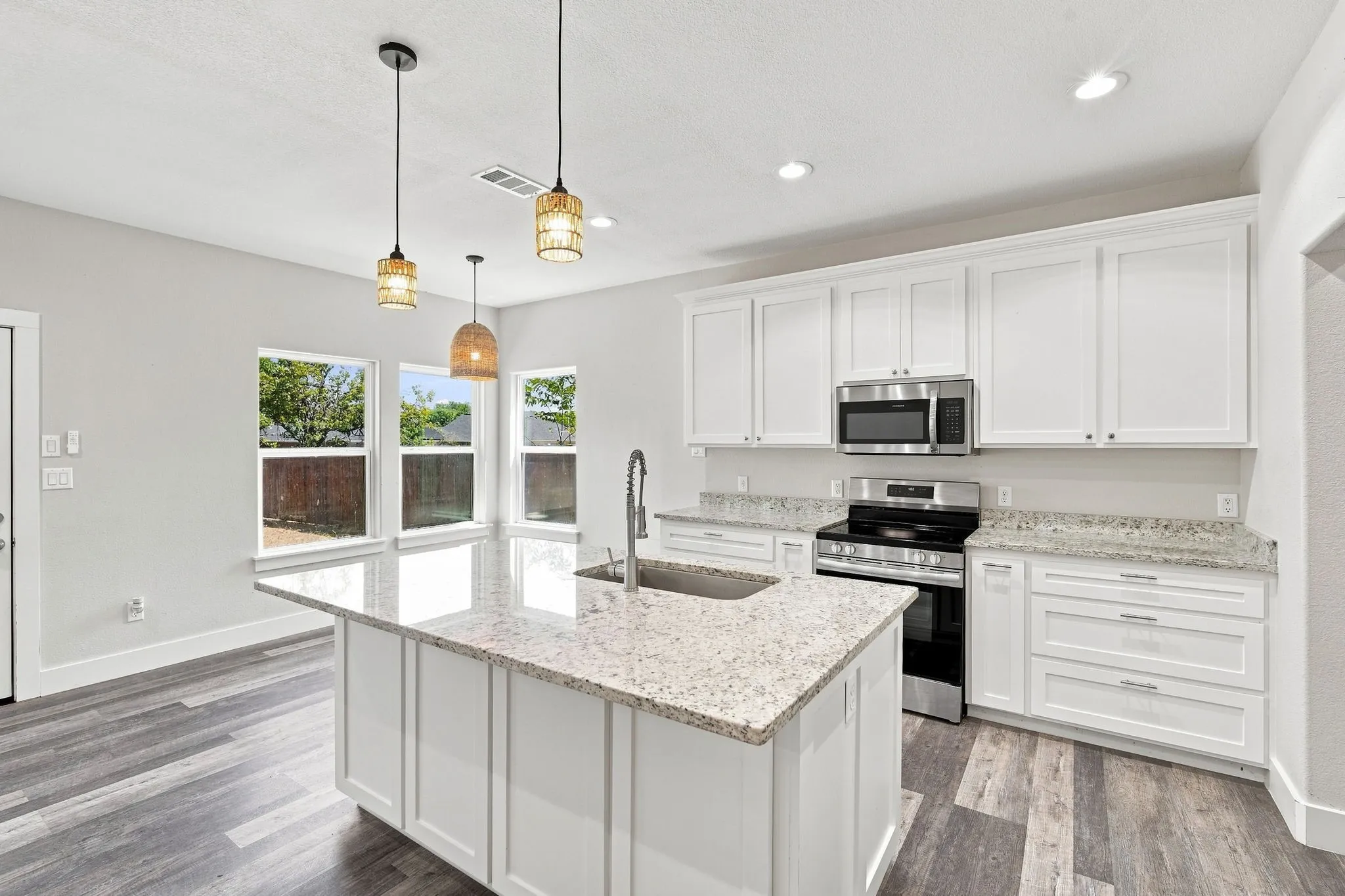 Kitchen featuring a center island with sink, white shaker-style cabinetry, stainless steel appliances, and light-toned countertops