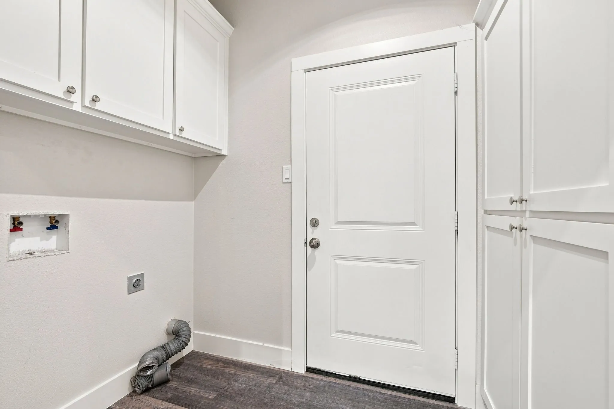 White shaker-style cabinetry, wood-finish flooring, white paneled door, and built-in storage
