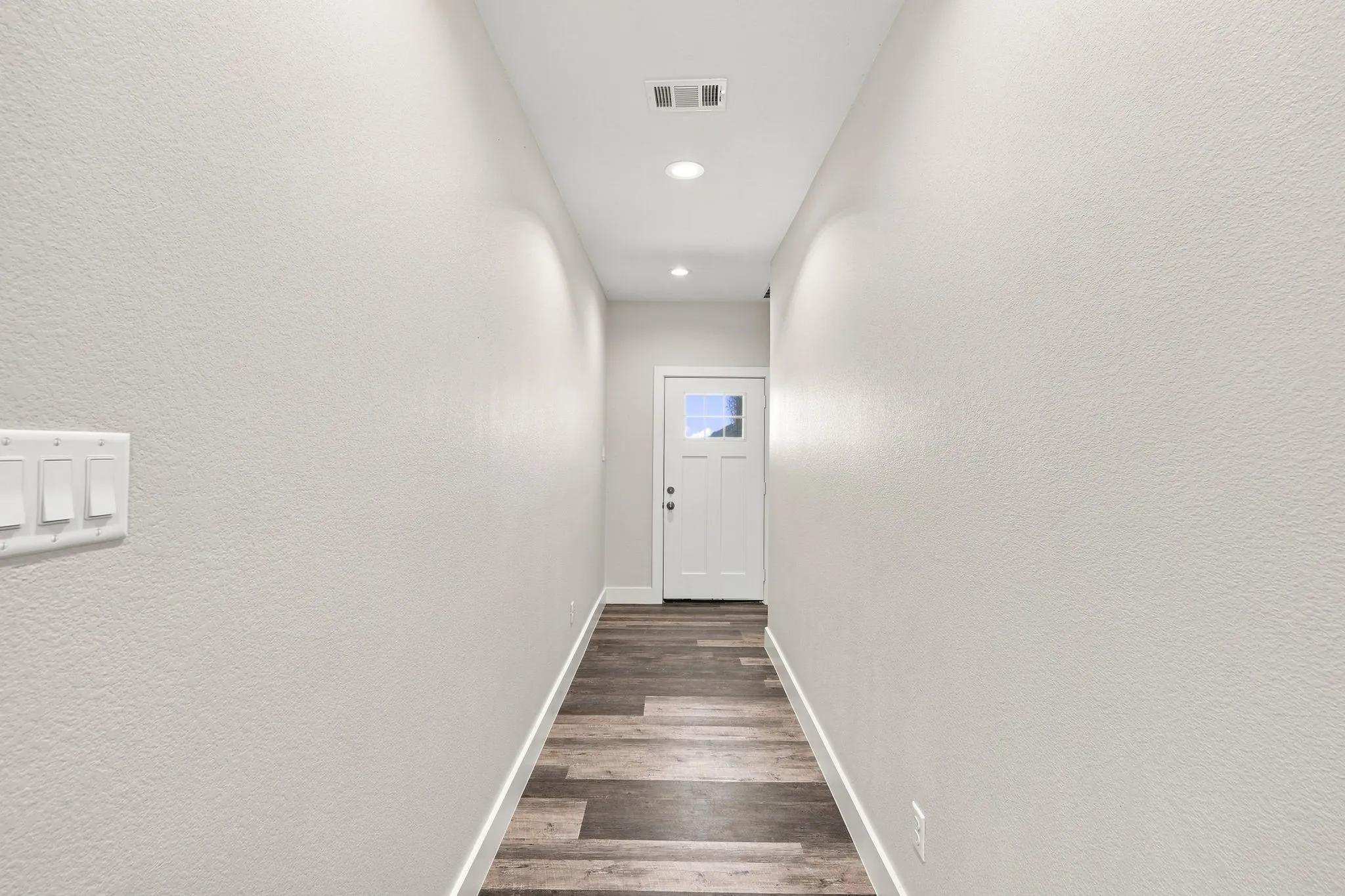 Recessed ceiling lighting, wood-finish flooring, white trim, and a white paneled door with window inserts