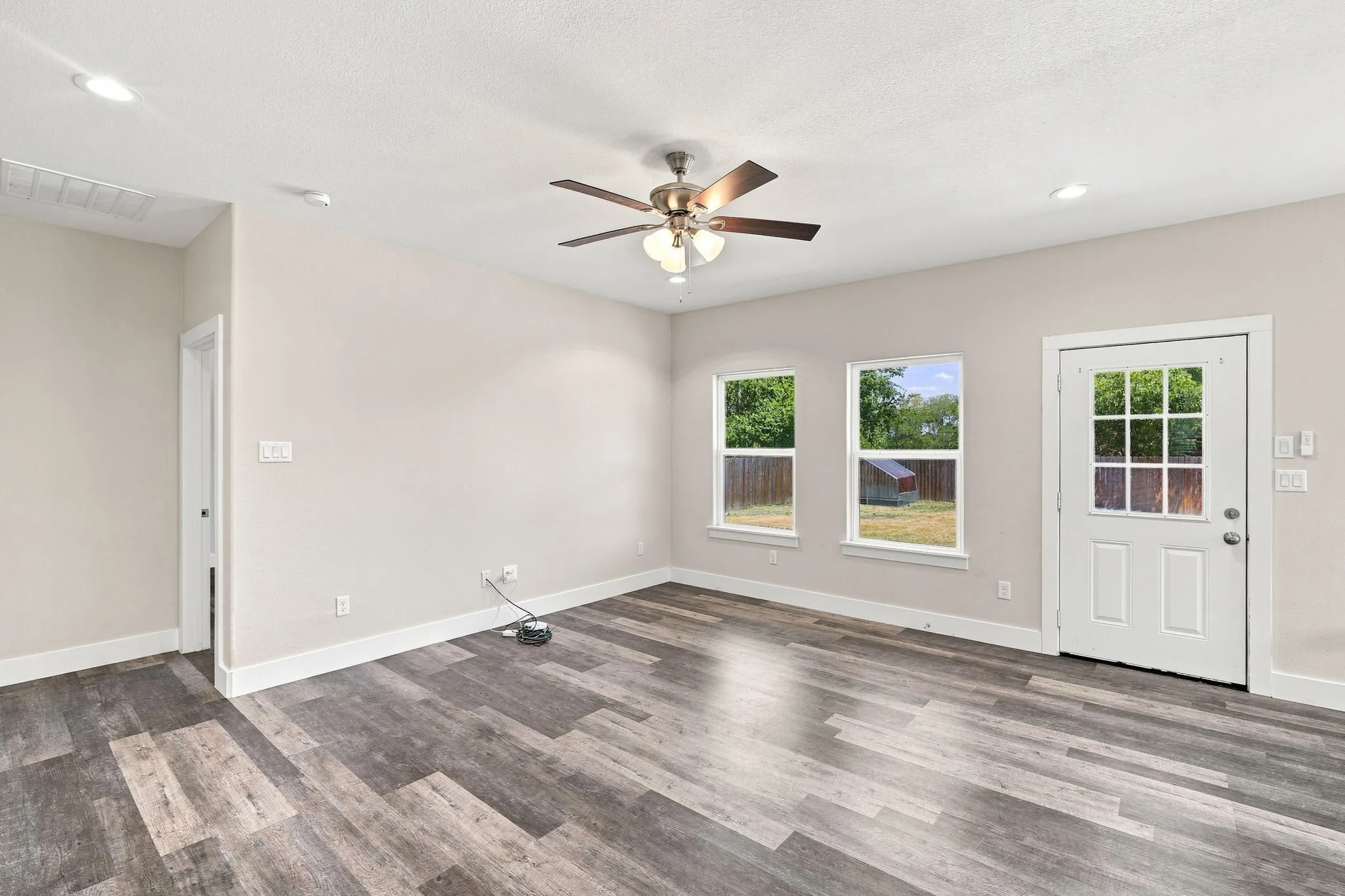 Wood-finish flooring throughout, ceiling fan, recessed lighting, white trim, and a white paneled door with window inserts