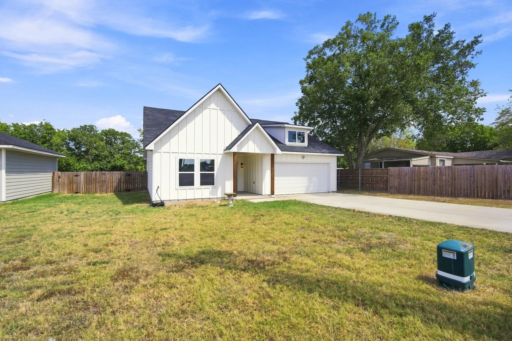 Modern farmhouse exterior with vertical white siding, black-framed windows, and a prominent gable