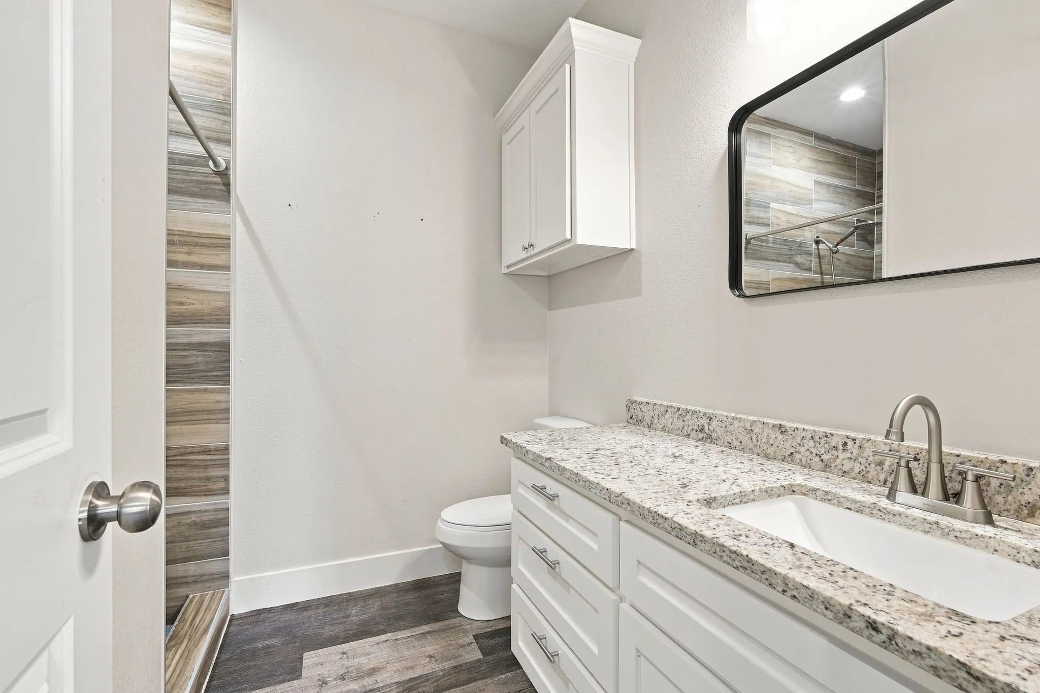 Vanity with white shaker cabinetry, undermount sink, and speckled countertop
