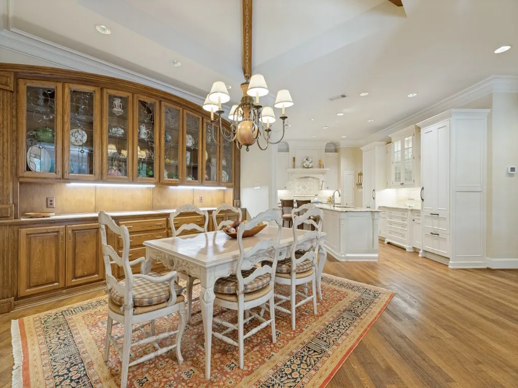 Hardwood flooring throughout, custom wood-finish cabinetry with glass fronts, recessed lighting, crown molding, and a spacious kitchen area with white cabinetry