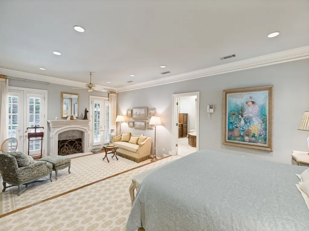 Recessed lighting, crown molding, double French doors, ornate fireplace with decorative screen, and a ceiling fan