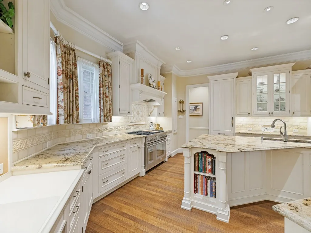 Custom cabinetry with glass-front accents, granite countertops, tile backsplash, wood-finish flooring, and recessed lighting