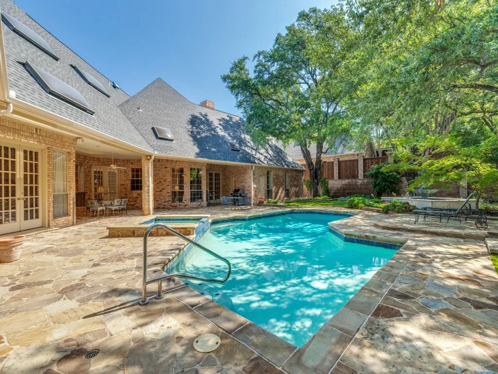 Freeform swimming pool with integrated spa, surrounded by flagstone paving