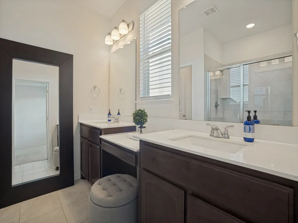 Dual vanity with integrated sinks, dark wood-finish cabinetry, light countertops, and a glass-enclosed shower