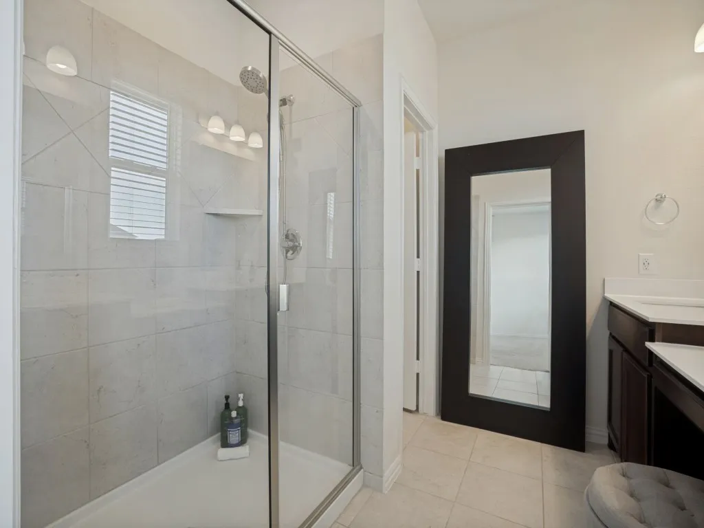 Tile-surround shower with glass enclosure, built-in shelving, and rain showerhead