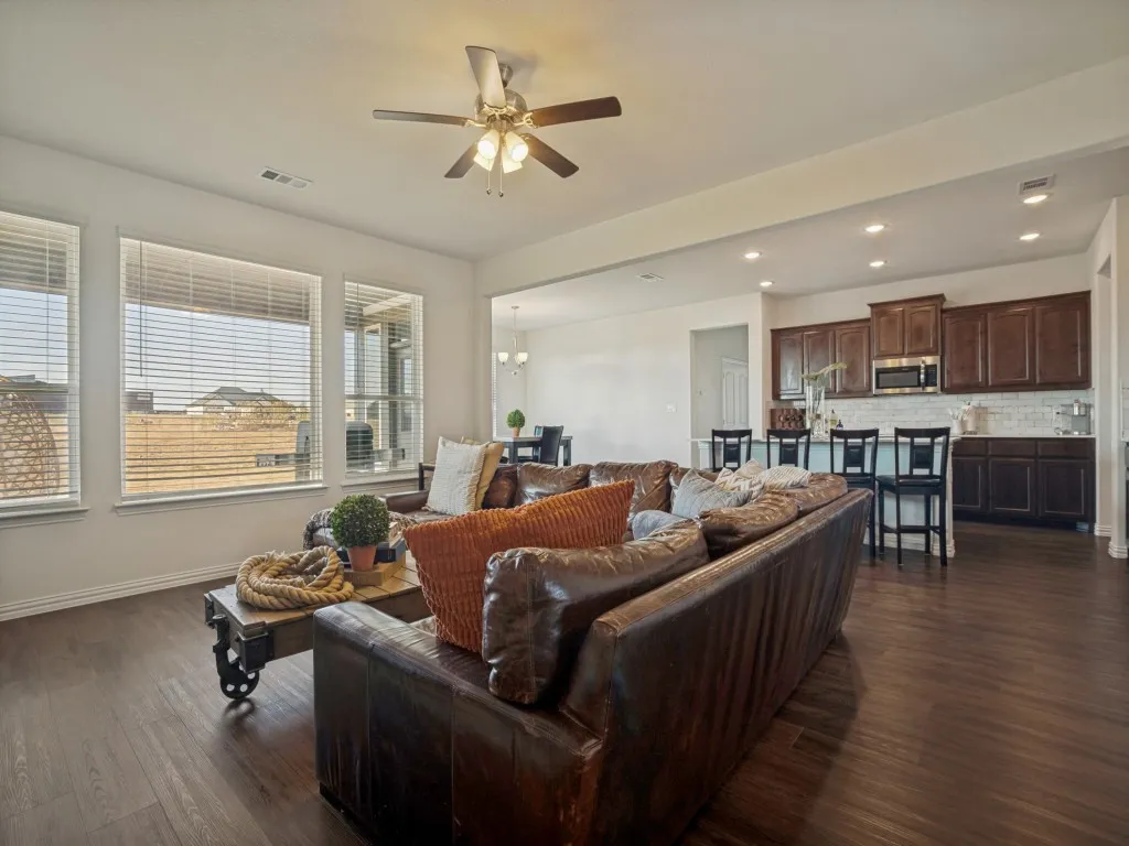 Open-concept living area with wood-finish flooring, recessed lighting, and multiple windows