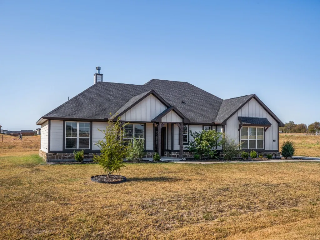 Contemporary craftsman-style residence featuring a dark shingle roof, light-colored siding, and dark trim accents