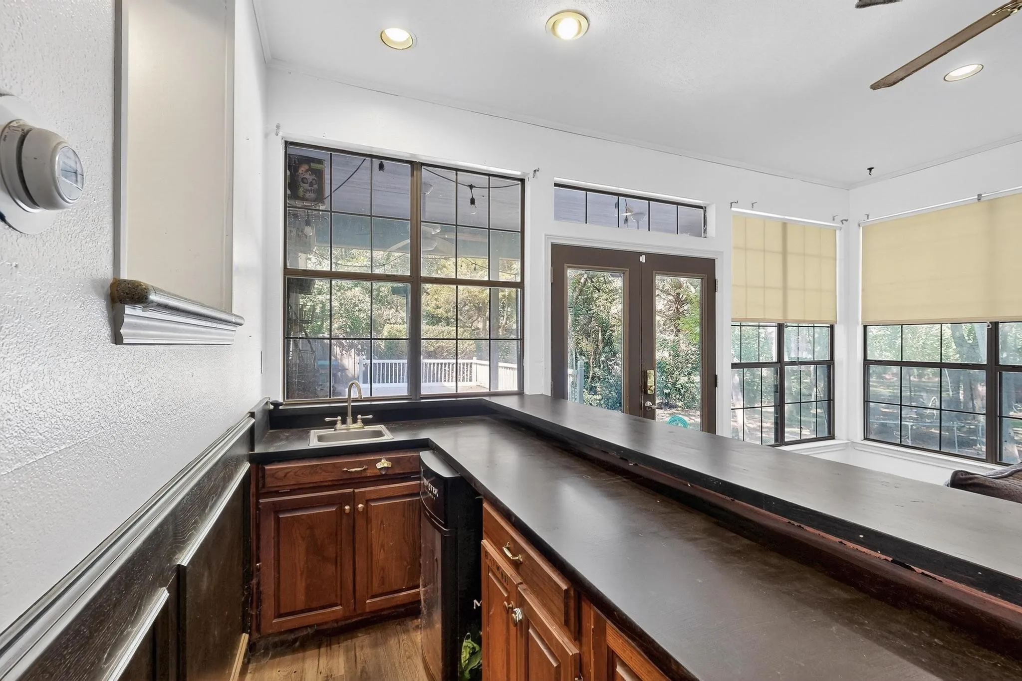 Bar featuring dark countertops, recessed lighting, a textured wall, a ceiling fan, and french doors