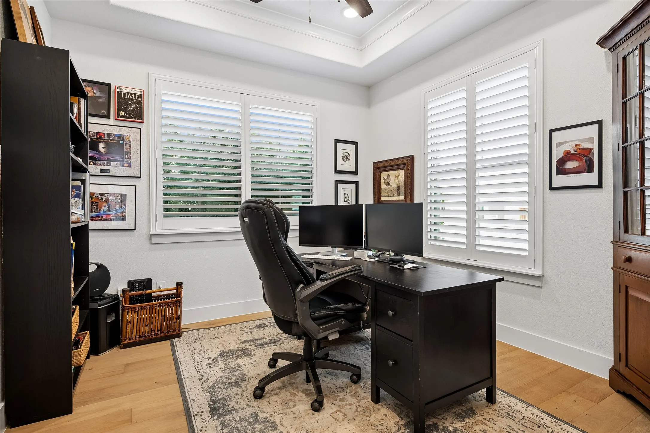 Private home office with hardwood flooring, shutters, and ceiling fan