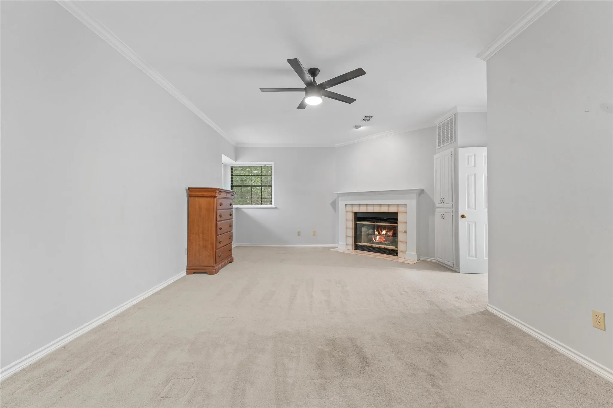Spacious primary suite with private fireplace, built-in storage, plush carpet, and room for oversized furniture in a quiet upstairs retreat.